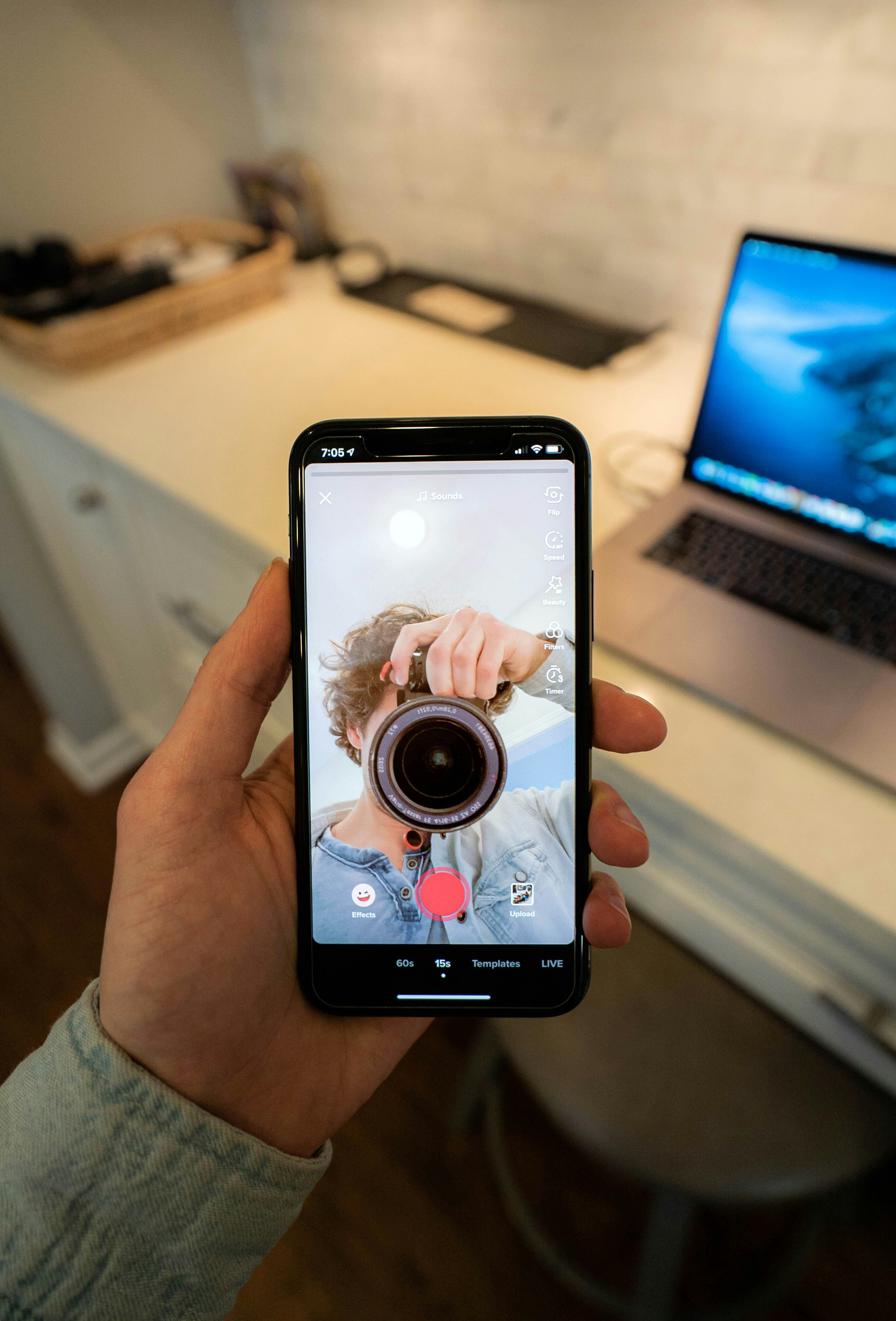 Imagen de una persona tomándose una foto con una cámara reflejado en su cámara frontal del teléfono