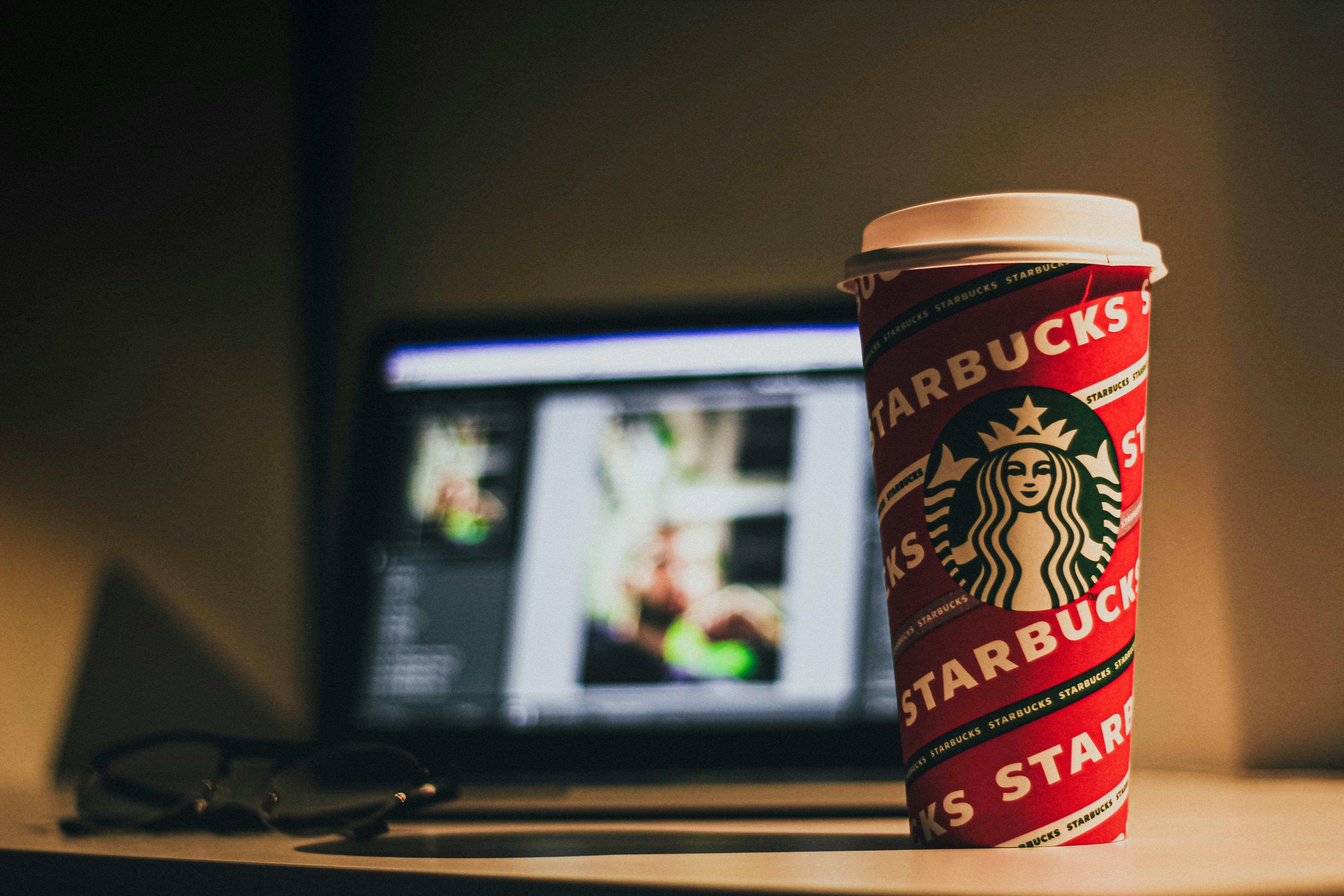 Imagen de un vaso rojo de Starbucks y de fondo una computadora