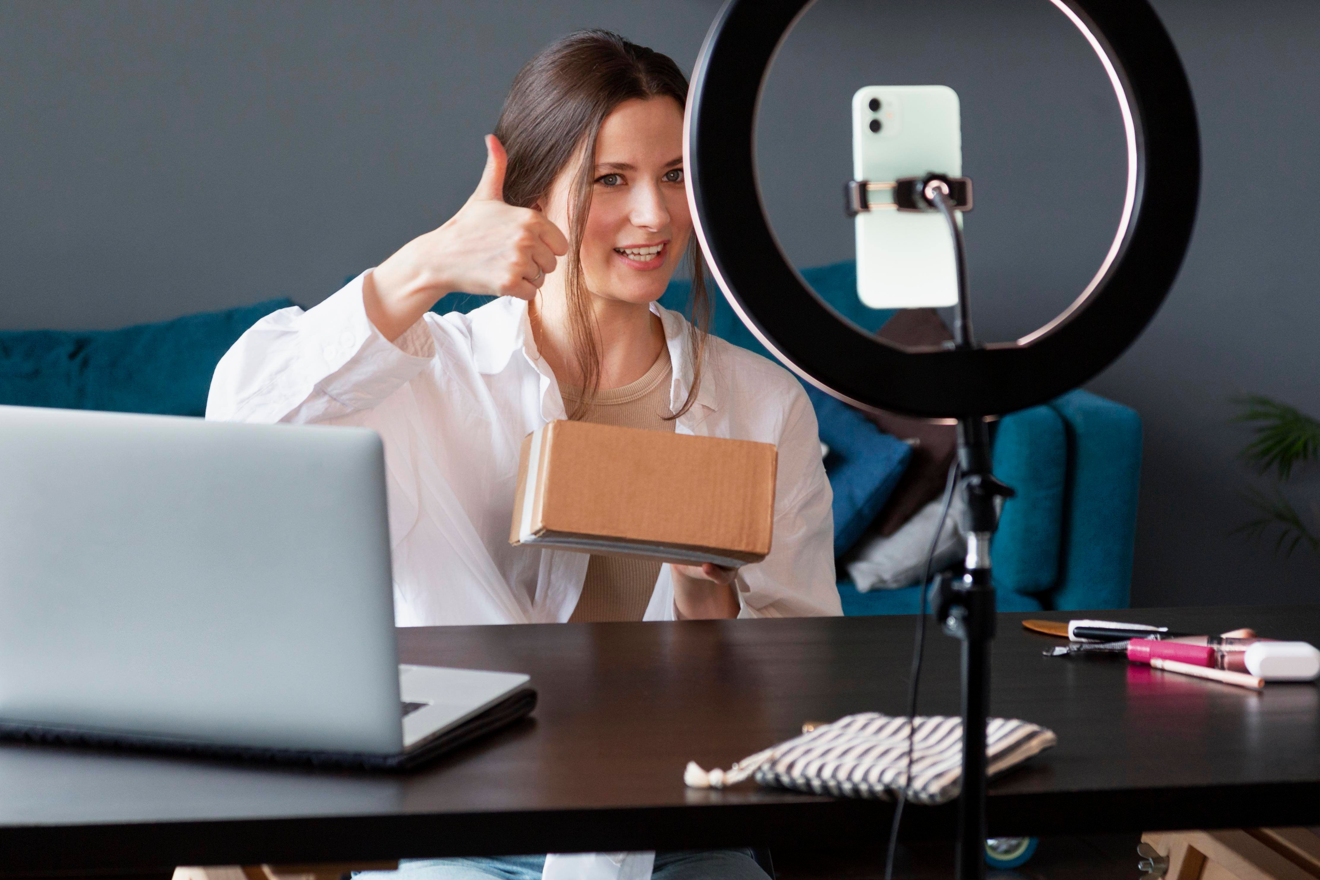 Una chica frente a un celular grabándose mientras hace reseñas de productos